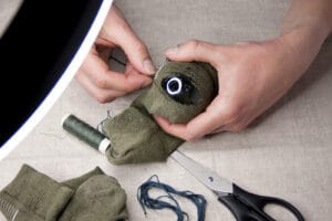Closeup Female Hands. Woman Sitting At Table Darning Holey Sock.